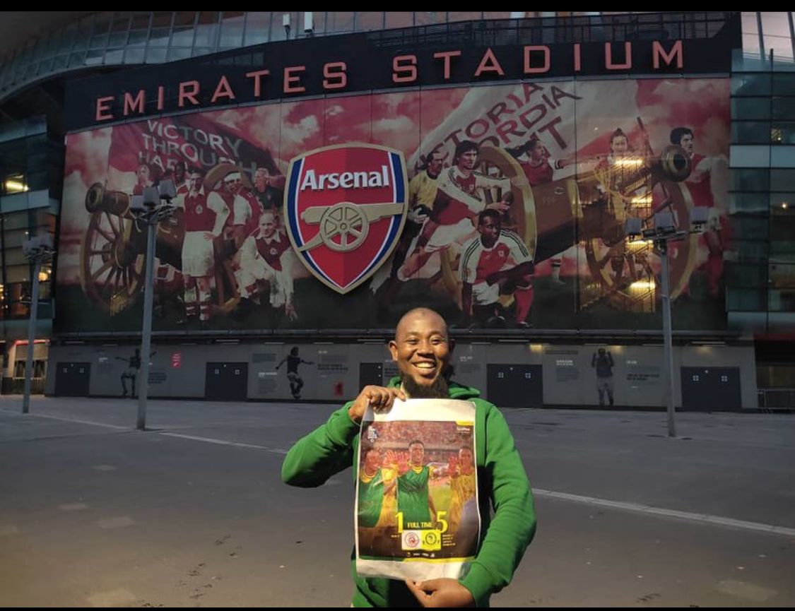 Shabiki wa Yanga na bango la 5g kwenye uwanja wa Arsenal
